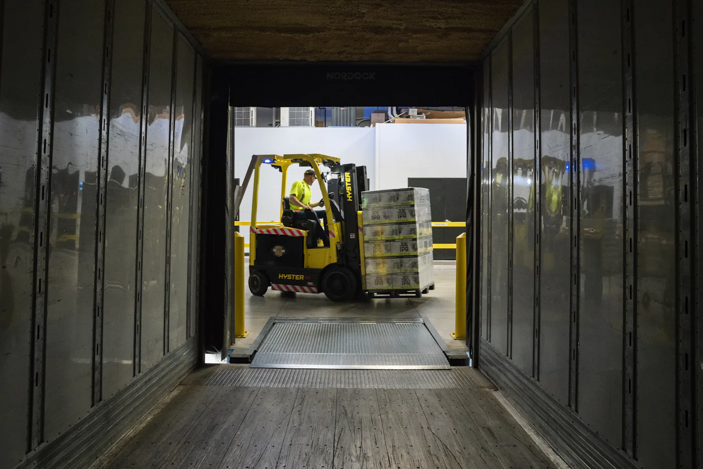 A forklift loading pallets into a trailer