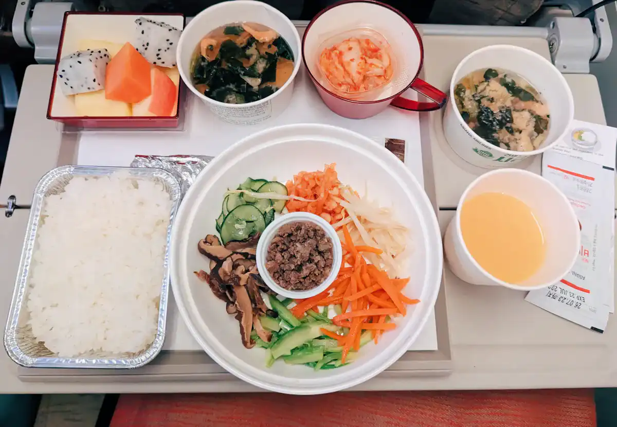 An airline meal tray with rice, vegetables, soup and sides
